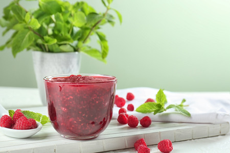Bowl with tasty raspberry jam on white table
