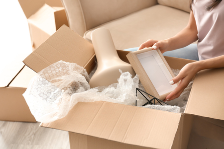 Young woman unpacking moving box at new homeの写真素材