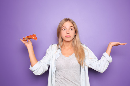 Emotional woman with slice of delicious pizza on color background