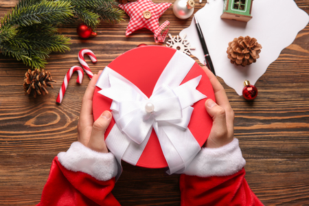 Santa Claus holding gift box on wooden table, top viewの写真素材