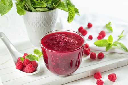 Bowl with tasty raspberry jam on white table