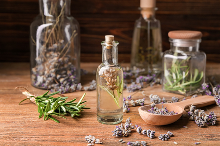 Bottle of essential oil with lavender and rosemary on wooden tableの写真素材