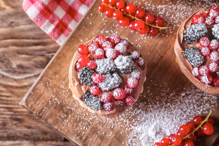 Tasty tartlets with berries on wooden board, top viewの写真素材