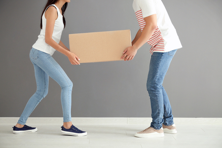 Young couple carrying big moving box at new homeの写真素材