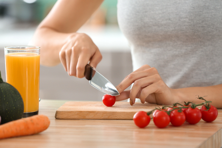 Young woman making fresh vegetable salad in kitchen, closeupの写真素材