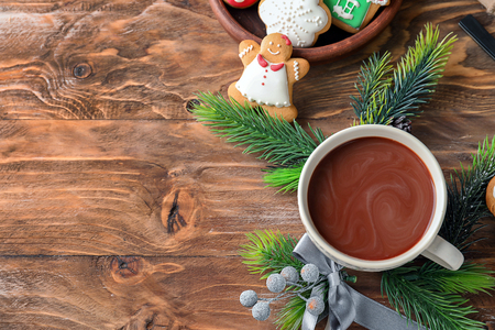 Cup of hot cocoa with fir tree branches and cookies on wooden tableの写真素材