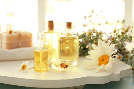 Bottles of essential oil with chamomile flowers on white boardの写真素材