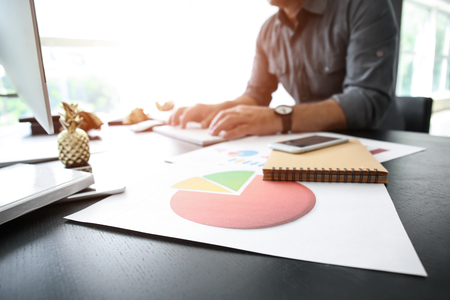 Diagram on table of businessman working with computer in officeの写真素材
