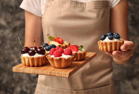 Woman holding tasty tartlets with berries, closeupの写真素材