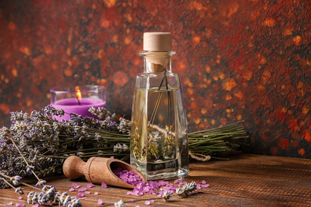 Bottle of lavender essential oil and scoop with sea salt on tableの写真素材