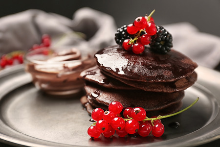 Delicious chocolate pancakes decorated with berries and sweet syrup on plate, closeupの写真素材