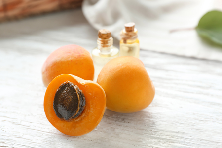 Fresh apricots and bottles of essential oil on wooden tableの写真素材