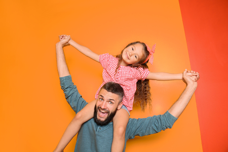 Funny portrait of father and his little daughter on color backgroundの写真素材