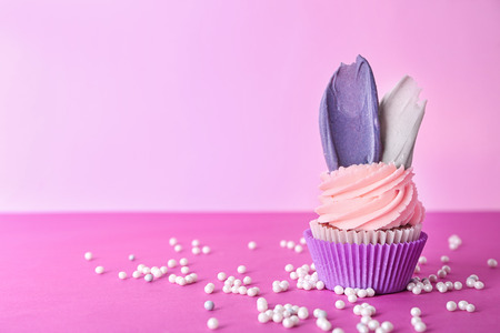 Creative birthday cupcake on color background