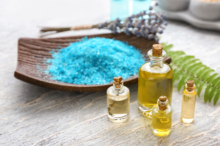 Bottles with essential oil and sea salt on wooden tableの写真素材