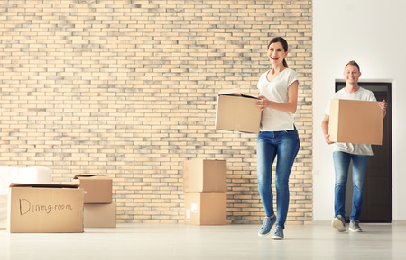Happy couple with cardboard boxes indoors. Moving into new houseの写真素材