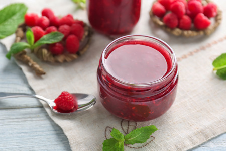 Jar with tasty raspberry jam on table