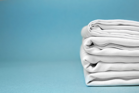Stack of clean bed sheets on color backgroundの写真素材