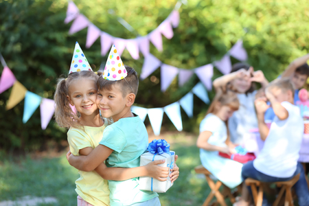 Cute little girl receiving Birthday gift from her friend outdoorsの写真素材