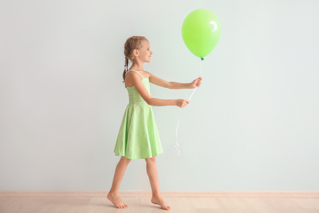 Cute little girl in with balloon near light wallの写真素材