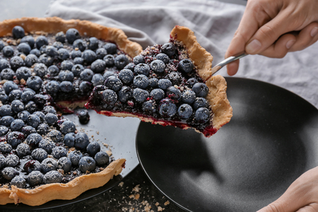 Woman putting piece of delicious blueberry pie onto plate, closeupの写真素材