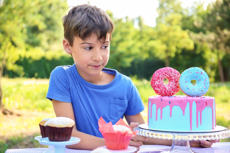 Cute little boy with cake celebrating Birthday outdoorsの写真素材