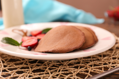 Plate with tasty chocolate pancakes on wooden table, closeupの写真素材