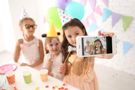 Cute little girls taking selfie while celebrating Birthday at homeの写真素材