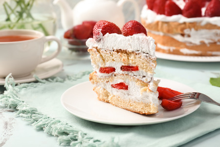Plate with piece of delicious strawberry cake on tableの写真素材