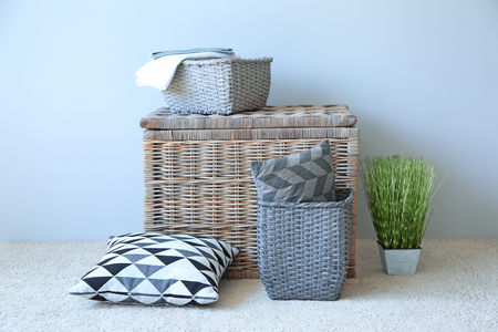 Soft pillows with wicker baskets near light wall indoorsの写真素材