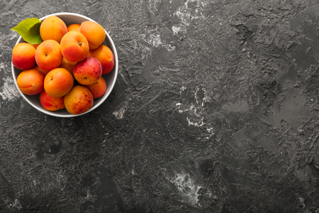 Bowl with fresh apricots on grunge tableの写真素材
