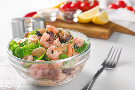 Bowl of delicious vegetable salad with seafood on tableの写真素材