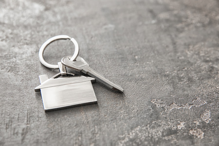 Key with trinket in shape of house on dark background. Mortgage conceptの写真素材