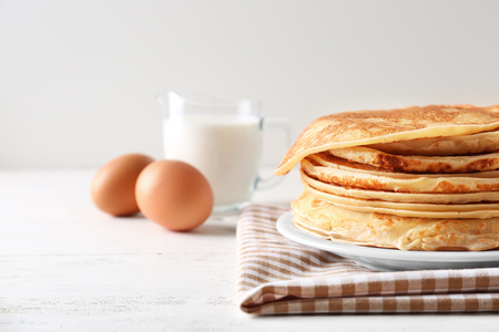 Plate with stack of tasty thin pancakes on tableの写真素材