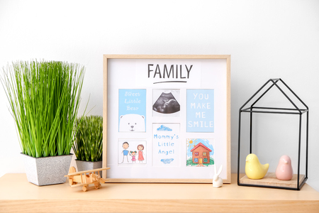 Frame with ultrasound photo and sweet words from mother to baby on tableの写真素材