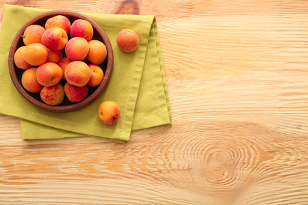 Bowl with fresh apricots on wooden tableの写真素材