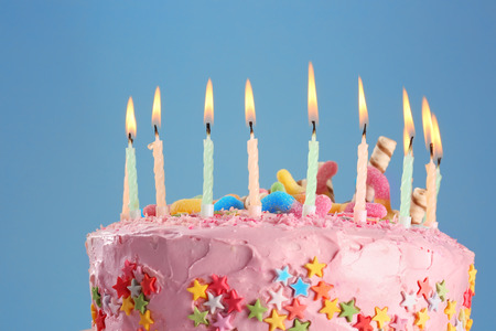 Tasty birthday cake with burning candles on color background, closeupの写真素材