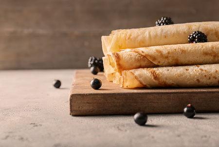 Delicious thin pancakes with berries on wooden boardの写真素材