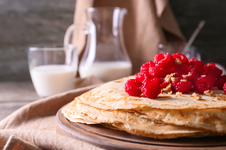 Delicious thin pancakes with berries and nuts on wooden board, closeupの写真素材