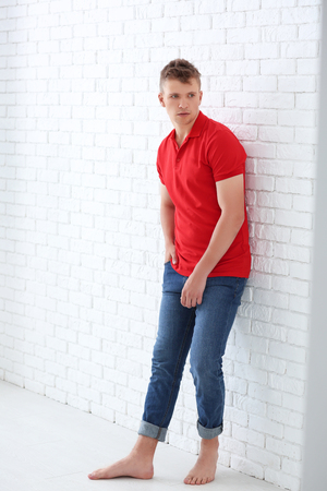 Portrait of handsome young man near white brick wallの写真素材