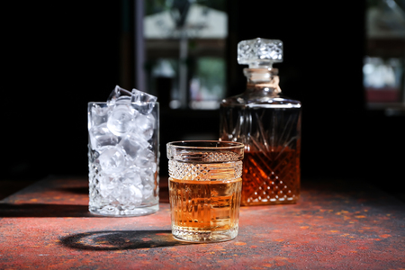 Glass of icy whiskey on color tableの写真素材