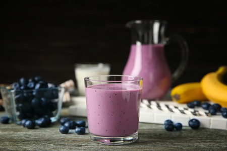 Glass of tasty blueberry smoothie on wooden tableの写真素材