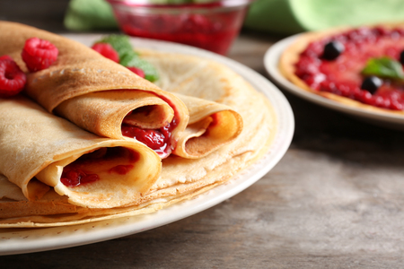 Rolled thin pancakes with sweet jam and berries on plate, closeupの写真素材