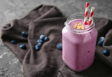 Glass jar of tasty blueberry smoothie on tableの写真素材