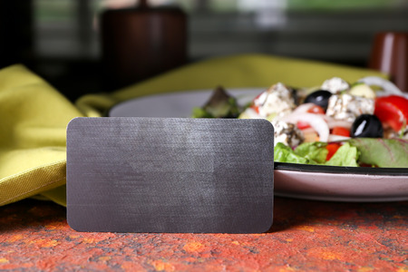 Blank card with tasty salad on color table