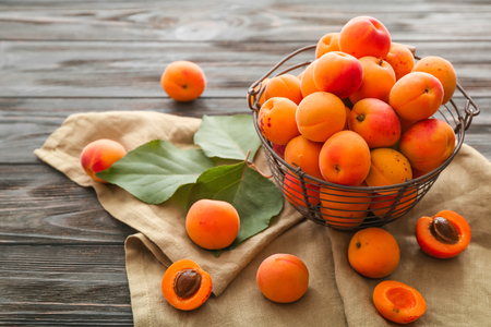 Basket with ripe sweet apricots on wooden tableの写真素材
