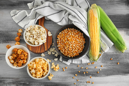 Composition with delicious popcorn and cobs on wooden backgroundの写真素材