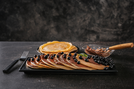 Delicious thin pancakes with berries and chocolate paste on dark tableの写真素材