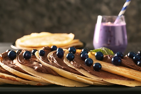 Delicious thin pancakes with berries and chocolate paste on plate, closeupの写真素材