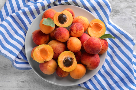 Plate with sweet ripe apricots on wooden tableの写真素材